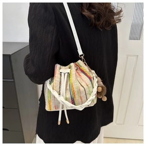 Detail of colorful vertical striped knit bucket bag with white drawstring and pompom charm
