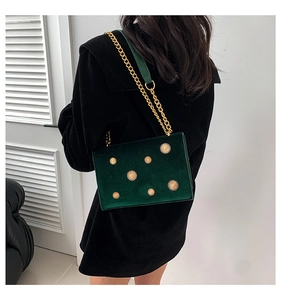 Détail du sac bandoulière en velours vert foncé avec rivets tournesol dorés et chaîne