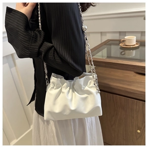 Detailed view of white pleated cloud bag with silver chain strap and metal ball decoration