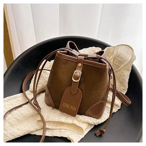 Detail of vintage brown bucket bag with contrast textures, drawstring and metal buckle