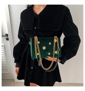 Détail d'un sac bandoulière en velours vert foncé avec rivets tournesol dorés et chaîne