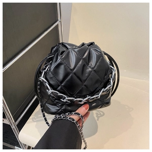 Detail of black quilted bucket bag with silver chunky chain and metal strap details