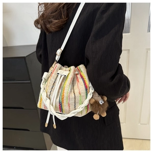Close-up of a woven bucket bag featuring colorful vertical stripes and a drawstring closure