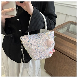 Détail du sac à paillettes avec un charm monstre en peluche rose et chaîne en métal