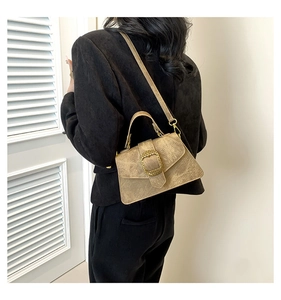 Detail view of khaki shoulder bag with vintage gold buckle on a model in a black suit