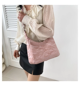 Detail of pink pleated texture shoulder bag with glossy finish and wide soft strap