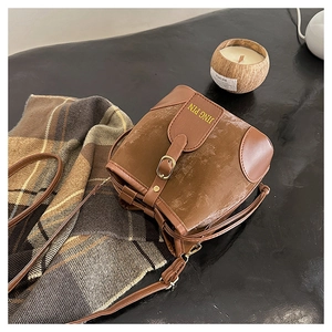 Detail view of retro brown crossbody bucket bag with gold lettering and check fabric lining