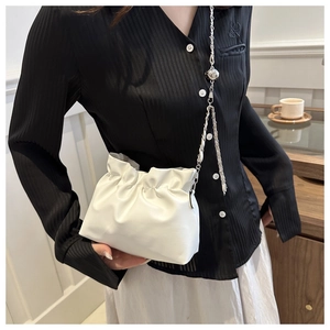 Detail shot of white pleated bucket bag with silver chain and sphere charm
