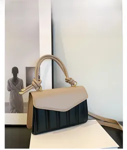 Close-up of khaki leather flap and black quilted body with gold hardware accents