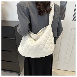 Back view of a model wearing a large white quilted corduroy crescent hobo shoulder bag