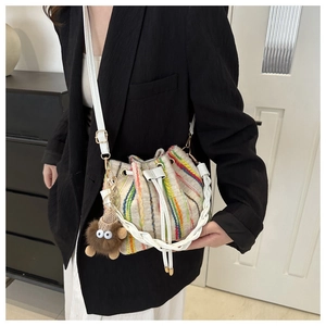 Detail of colorful striped woven bucket bag with drawstring closure and cute plush charm