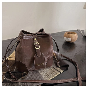 Detailed shot of a brown leather bucket bag with drawstring closure and metal buckle