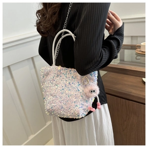 Détail du sac à main blanc à paillettes avec breloque rose duveteuse et chaîne argentée