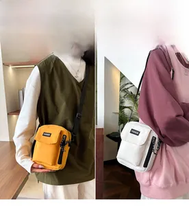Detail view of yellow and white nylon crossbody bags with flap pocket and fashion label