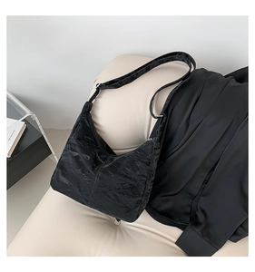 Detail shot of the black pleated texture fabric and silver metal buckle on the shoulder bag