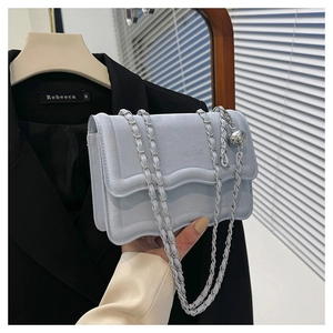 Close-up of light blue velvet bag with wave flap, silver chain, and metal ball charm