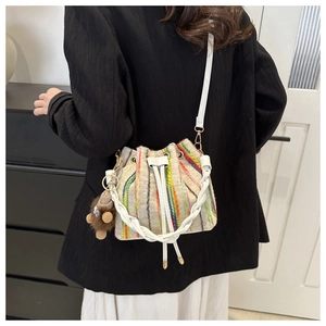 Detailed view of the colorful striped knit bucket bag with a cute plush bear charm