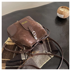 Close-up of the vintage brown leather bucket bag with JING PIN logo and flap design