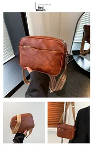 Close-up of reddish brown crossbody bag featuring V-shaped quilting and a wide woven strap