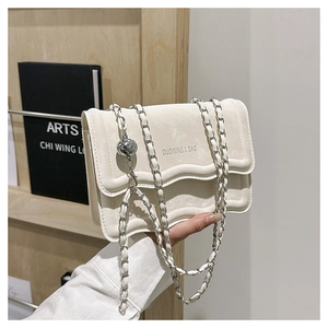 Detail of cream wavy crossbody bag with chain strap and silver decorative ball
