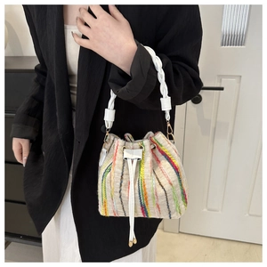 Detail of colorful striped knitted bucket bag with drawstring closure and woven handle
