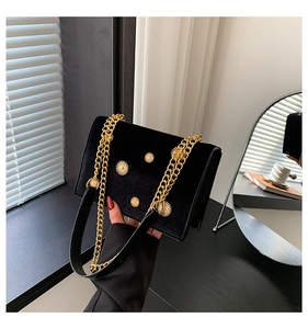Détail d'un sac bandoulière en velours noir avec ornements tournesol dorés et chaîne chic