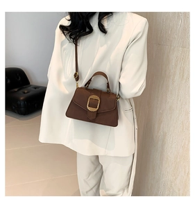 Close-up of a vintage mocha brown shoulder bag with a large golden buckle detail
