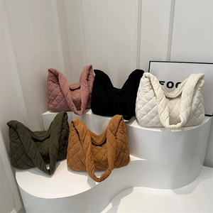 Quilted corduroy tote bags shown in five colors on a minimalist display stand