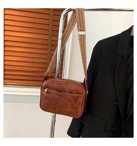 Macro view of brown leather crossbody bag featuring classic diamond quilted texture