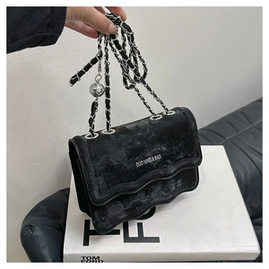 Detail showing the wavy flap edge and silver chain of this black velvet crossbody bag