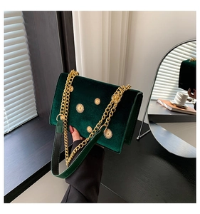 Vue détaillée du velours vert foncé et des rivets floraux dorés sur le sac à chaîne