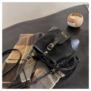 Detail of vintage black bucket bag with contrast stitching on brown checkered scarf