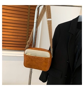 Detail of color-block camera bag with quilted stitching and wide woven shoulder strap