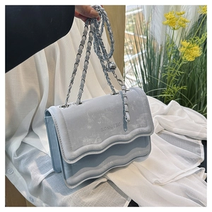 Detail of light blue wave-patterned shoulder bag with silver chain and metal ball charm