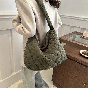 Olive green corduroy quilted tote bag shown in a cozy interior cafe setting