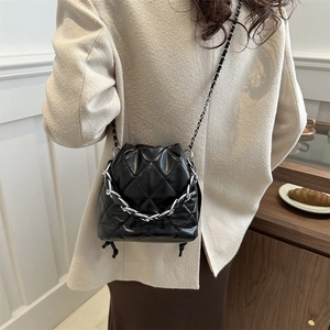 Fashionable black quilted bucket bag with silver chain strap for women in urban style