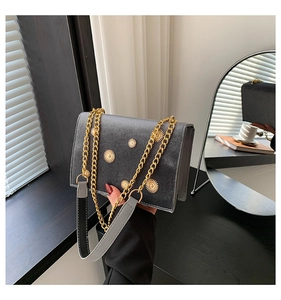 Détail d'un sac à main en velours gris orné de décorations métalliques en forme de soleil doré