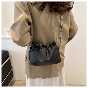 Detail of black pleated cloud bucket bag with silver chain strap and metal ball adjuster