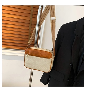 Detail of a color-block crossbody bag featuring brown leather and woven bohemian strap