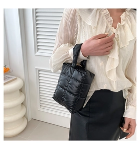 Detail of black quilted puffer tote bag showing glossy nylon fabric and padded texture