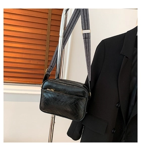 Detail of black quilted crossbody bag with stylish black and white geometric wide strap