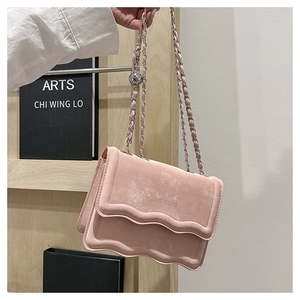 Detailed view of pink suede shoulder bag with wave edges and decorative silver chain