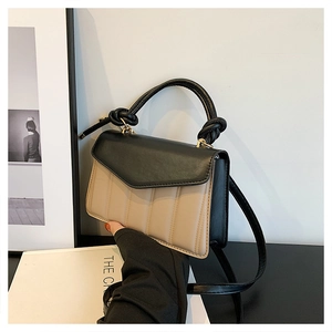 Close-up of stylish contrast color crossbody bag with quilted beige texture and black handle