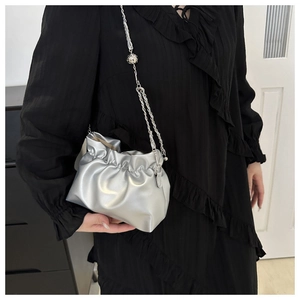 Detail of silver pleated bucket bag with metallic luster and sleek chain shoulder strap
