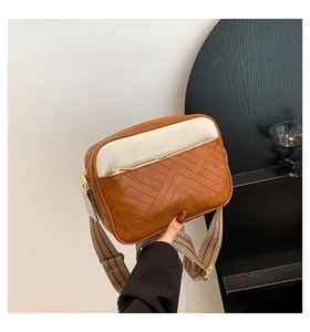 Detail of color-block crossbody bag with V-quilted stitching and wide woven strap