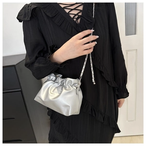 Detail of silver pleated bucket bag with metallic finish and delicate chain strap