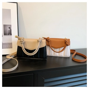 Detailed view of color-block handbags with vertical quilting and decorative knotted handles