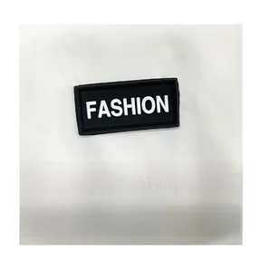 Close-up of black rubber FASHION logo patch on white nylon fabric of crossbody bag