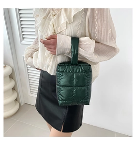 Detail of dark green quilted tote bag showing puffer texture and padded handle on model