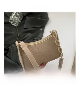 Detail of beige crocodile pattern underarm bag with gold chain and wide shoulder strap
